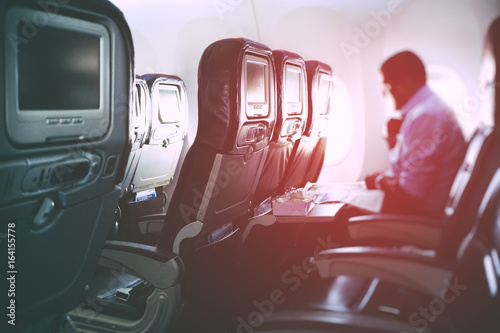 Blurry image of airplane interior with incidental passenger sitting on seats - travel concept, retro styled.