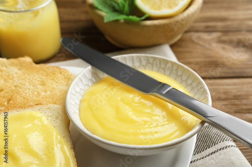 Delicious lemon curd and fresh toasts on wooden table, closeup