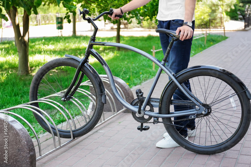 Young man parking bicycle outdoors