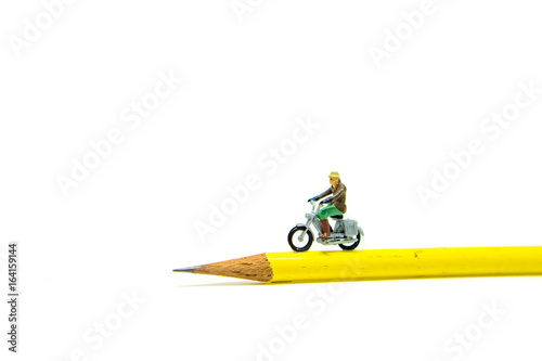 Miniature people, traveler riding on yellow pencil isolated on white background using as exploring on earth concept