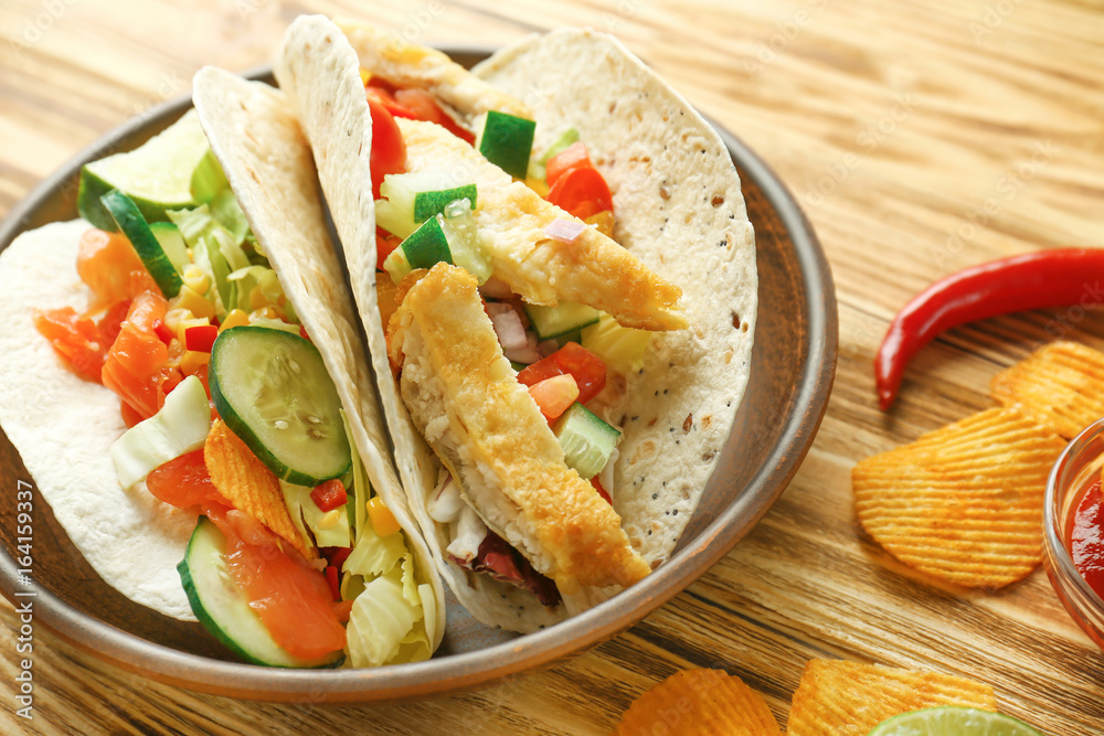 Tasty fish tacos on plate with chips on wooden background Tasty fish tacos on plate with chips on wooden background