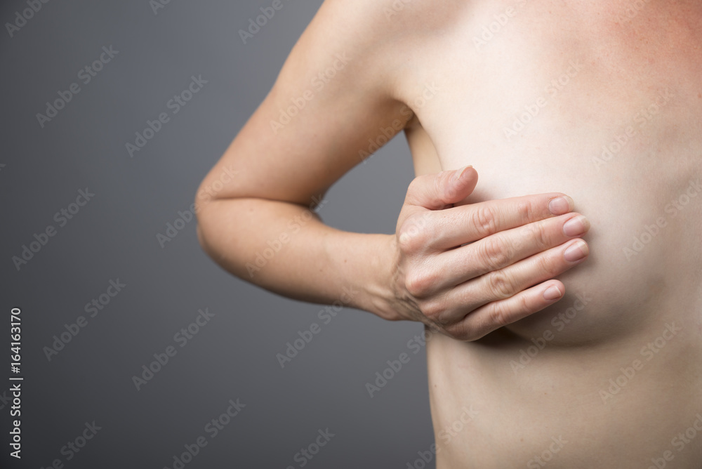 Closeup cropped portrait young woman with breast pain touching chest colored isolated on background