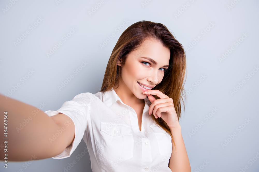 Selfie time! So hot and pretty! Attractive young lady is making a selfie on the camera, flirty and playful. In casual wear, on pure light background Selfie time! So hot and pretty! Attractive young lady is making a selfie on the camera, flirty and playful. In casual wear, on pure light background