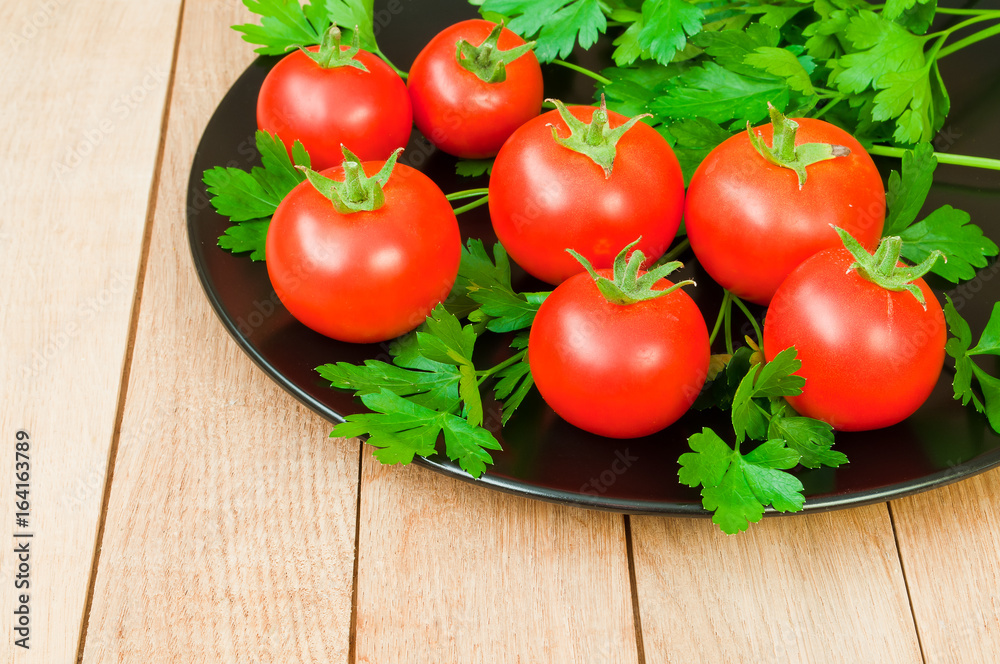 Fresh red tomatoes on a dark plate on a wooden table Fresh red tomatoes on a dark plate on a wooden table