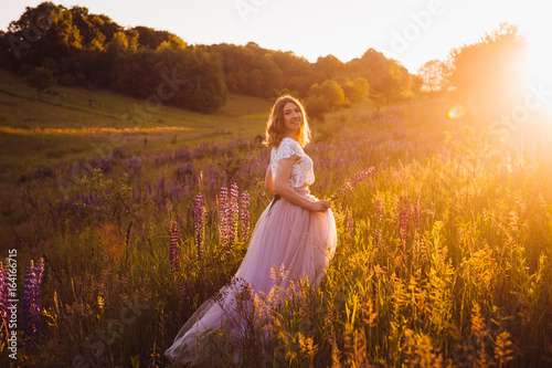 Wallpaper Mural Stunning woman in bright dress walks across the field in the rays of sunset Torontodigital.ca