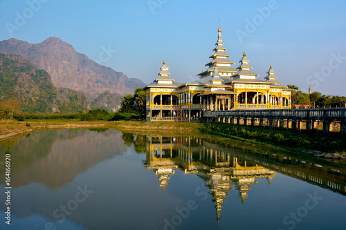 Kyaut Ka Lat Buddhist Temple reflecting in the water of the lake at sunset. Hpa-An, Myanmar. photo