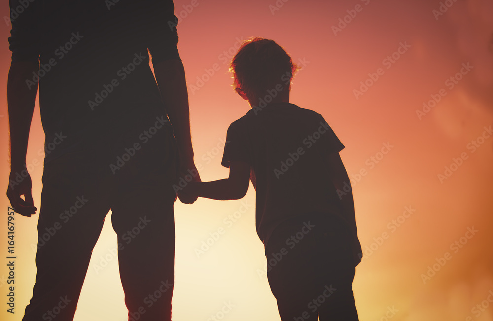 silhouette of father and son holding hands at sunset silhouette of father and son holding hands at sunset