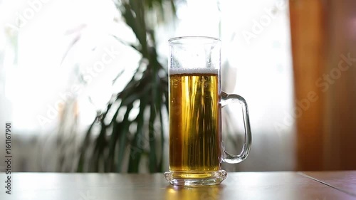 Half empty beer mug on table / Half empty beer mug on table indoors. Vertical panorama. photo