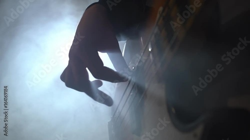 Man playing bass guitar at a rock concert. closeup