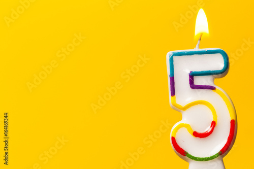 Photography Number 5 birthday celebration candle against a bright yellow background