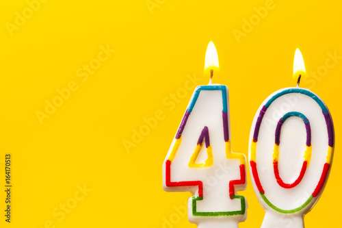 Number 40 birthday celebration candle against a bright yellow background photo
