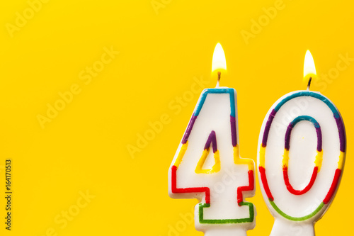 Number 40 birthday celebration candle against a bright yellow background