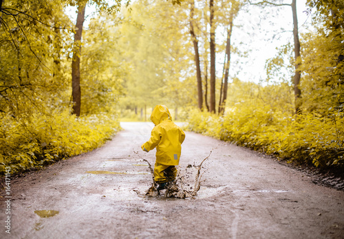 Obraz na plátně Little girl jumping fun in a dirty puddle