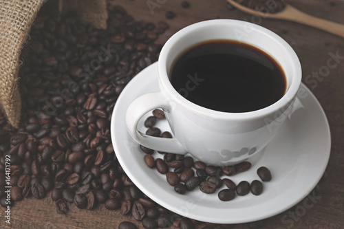 coffee cup and coffee beands on wood background.