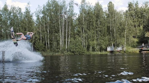 Wakeboarder making tricks on the sea or lake. Wakeboarding. Water sports on the beach. Extreme trick in air, surfing skateboard flip.