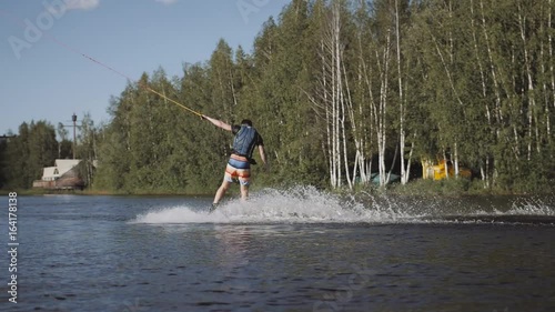 Wakeboarder ride on cable wakeboard in park, outdoor extreme slow motion on water, surfing athlete on water