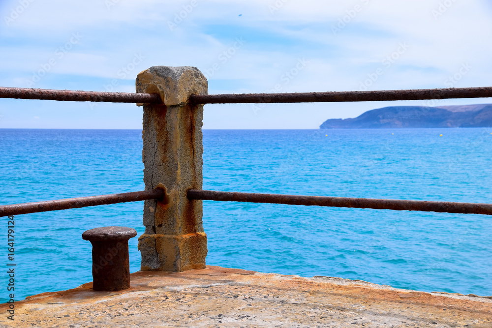 Fototapeta premium Concrete post of rusty ship bollard at the end of a concrete pier overlooking the Atlantic Ocean