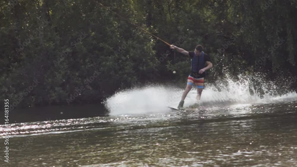 Wakeboarder ride on cable wakeboard in park, outdoor extreme slow motion on water, surfing athlete on water Wakeboarder ride on cable wakeboard in park, outdoor extreme slow motion on water, surfing athlete on water