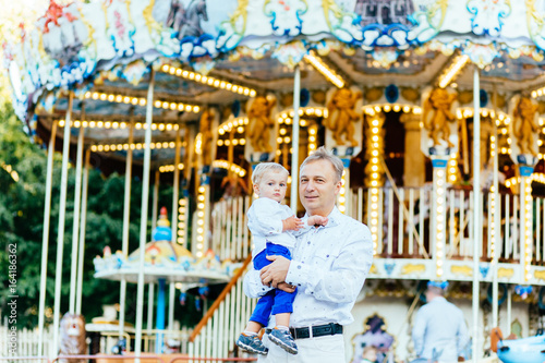 Father and son playing in amusement park at the evening time. Concept of friendly family