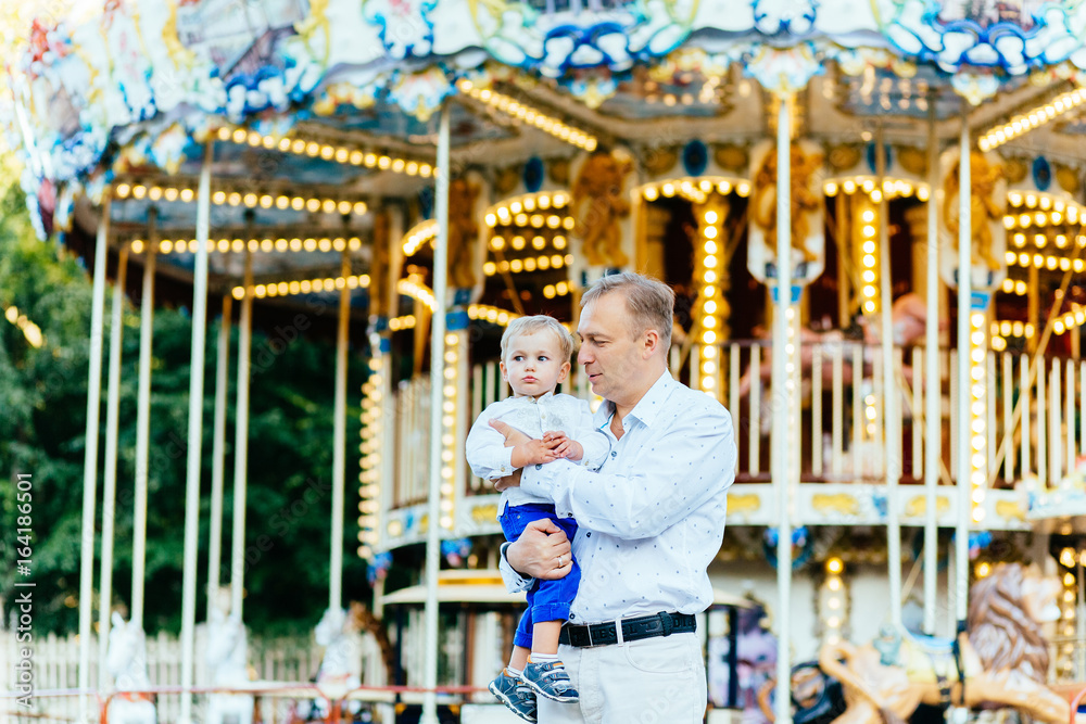 Father and son playing in amusement park at the evening time. Concept of friendly family Father and son playing in amusement park at the evening time. Concept of friendly family