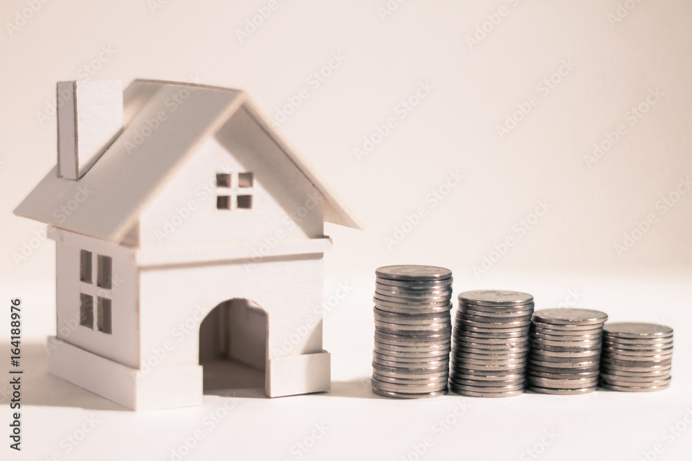 A family and home with model and coin stack on paper background, the saving money for real estate owner in the future concept. A family and home with model and coin stack on paper background, the saving money for real estate owner in the future concept.