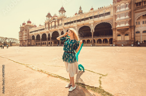 Romantic female tourist in blue watching famous building of the royal Palace of Mysore in Indo-Saracenic style, Karnataka state, India. photo