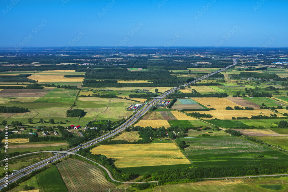 Flying above earth. Aerial view above road with meadows and fields.