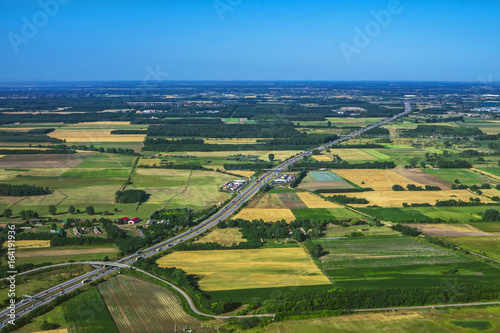 Flying above earth. Aerial view above road with meadows and fields.
