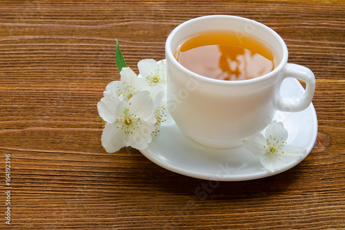 White mug of tea with jasmine on a wooden table. Close up, top view