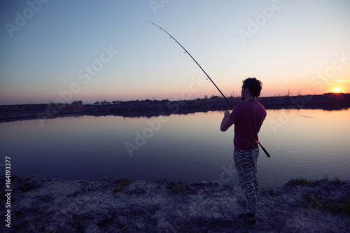 Young man fishing at pond and enjoying hobby © NDABCREATIVITY