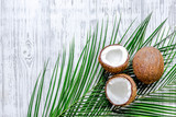 Appetizing cocount and palm branch on wooden table background top view copyspace
