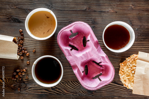 Coffee take out. Coffee cups with covers, coffee beans and cookies on wooden table backound top view photo