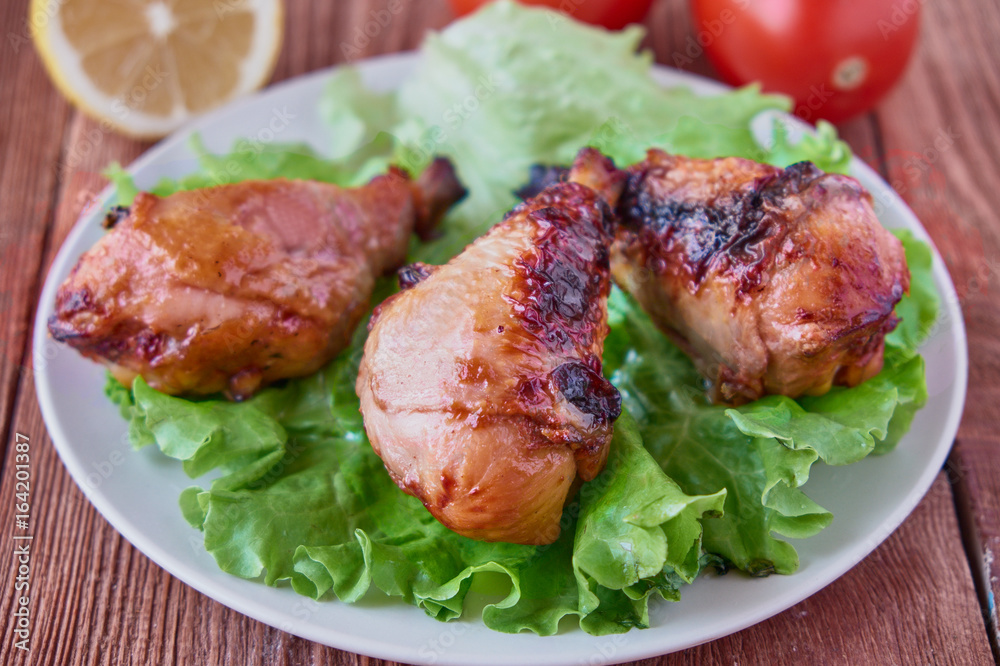 Grilled chicken legs with vegetables and lemon on a wooden background Grilled chicken legs with vegetables and lemon on a wooden background
