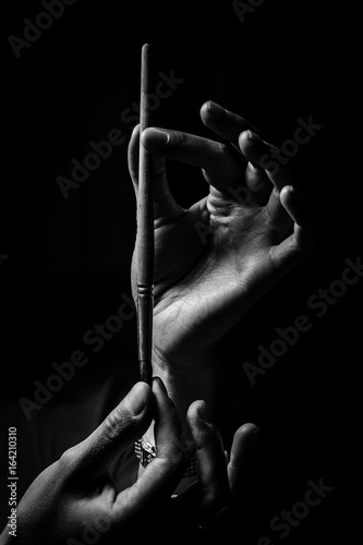 The artist's hands hold a brush