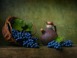 Still life with grapes on a basket and jug