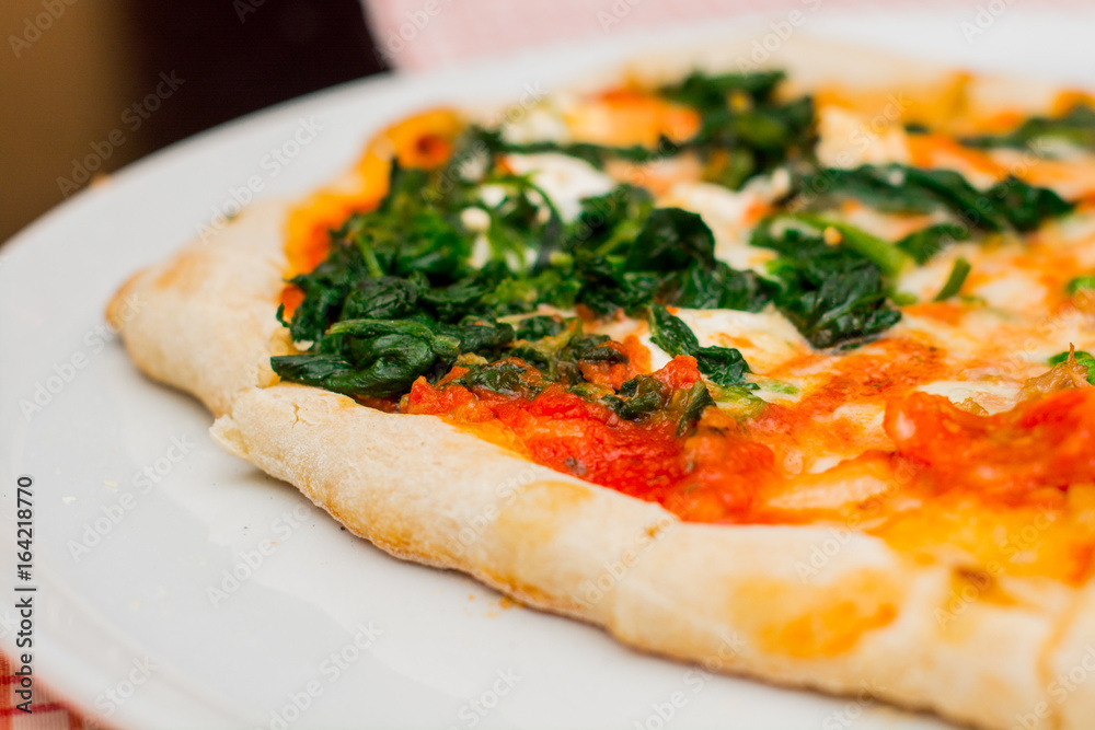 Fresh baked pizza with melted cheese, Italian herbs and tomato sauce and fresh basil on a white plate. Italian food, menu, restaurant concept Fresh baked pizza with melted cheese, Italian herbs and tomato sauce and fresh basil on a white plate. Italian food, menu, restaurant concept