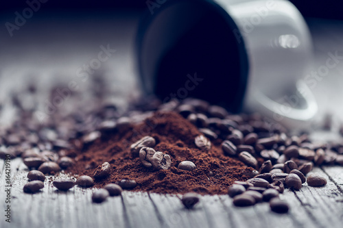 Cup of porcelain with coffee beans in foreground in vintage style.