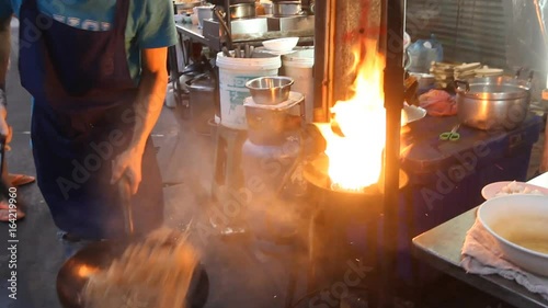 Chef preparing food with stir fry. Street food at Yaowaraj road in Bangkok. photo