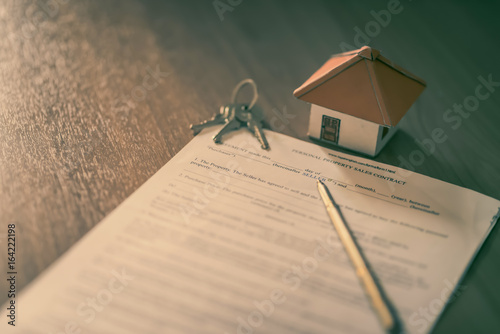 House keys on the rental agreement or the buy home contracts with the real estate property background. photo