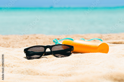 Sunglasses, Sunscreen Lotion And Slippers On The Beach