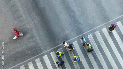 the one man walk converse,  the busy city crowd move to pedestrian crosswalk on businees traffric road (Aerial photo, top view)