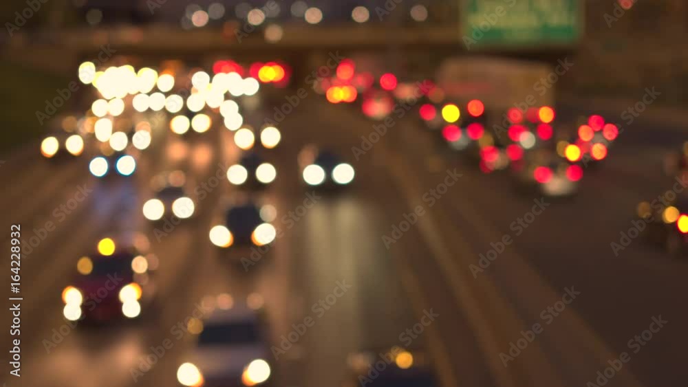 Defocused bokeh cars, SUVs, pickup trucks and semi-trailer trucks caught in traffic jam on busy multiple lane highway through Chicago city at night