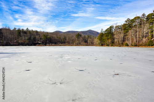 Frozen wintry landscape of cracked ice full of holes at Lake Powhatan in North Carolina