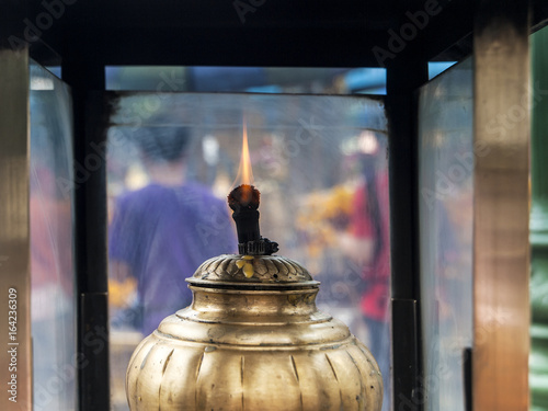 A single oil lamp burns at Erawn Shrine in central Bangkok, Thailand