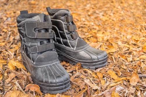 A pair of black boots on Dry leaves background.