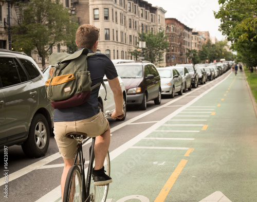 Back view of modern hipster man riding bike on bike lane in the city © goofyfoottaka