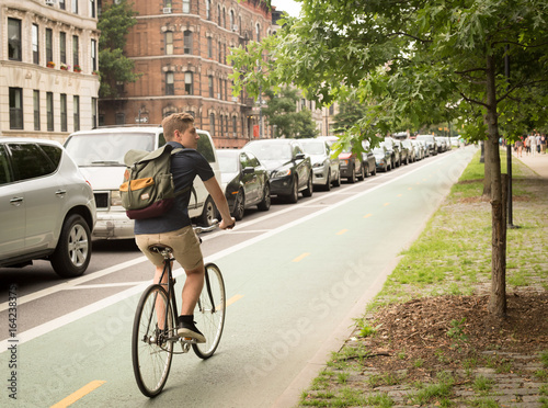 Photography Back view of modern hipster man riding bike on bike lane in the city