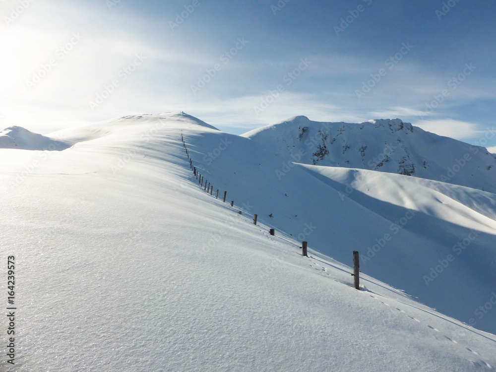 mountain ridge in the Swiss Alps in high winter with fence posts under deep snow