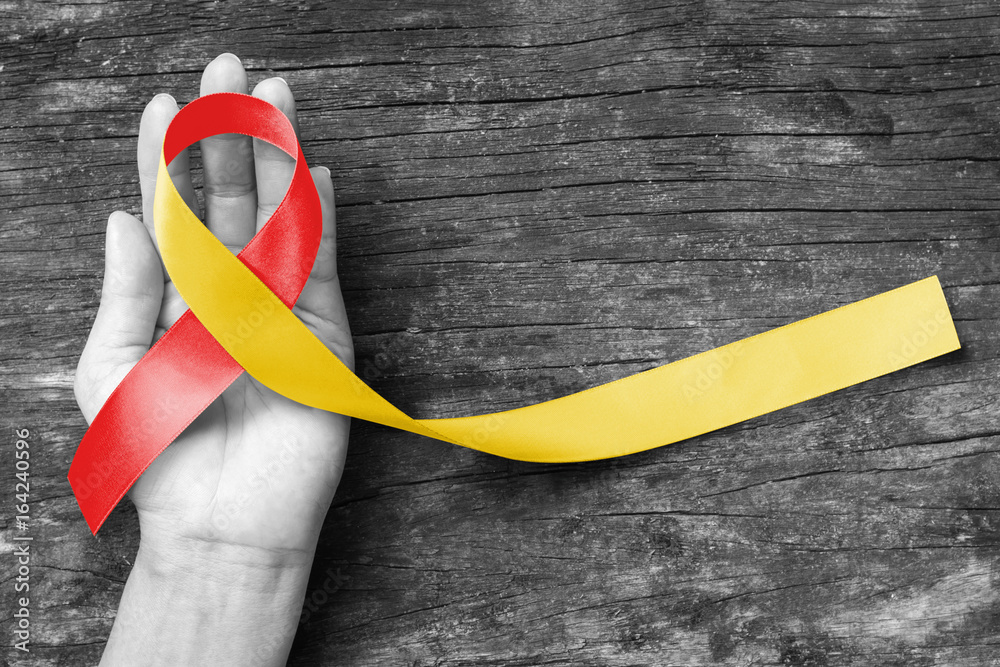 World hepatitis day and HIV/ HCV co-infection awareness with red yellow ribbon  (isolated  with clipping path) on person's hand support and old aged wood - obrazy, fototapety, plakaty 