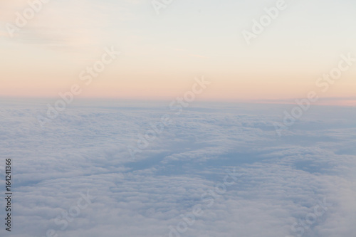 flying above the clouds at sunset landscape from an airplane photo